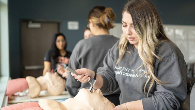 Image shows a PA student practicing a procedure on a mannequin.